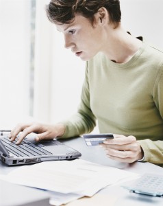 Woman Sits at a Desk Using a Laptop and Paying a Bill Online With Her Credit Card